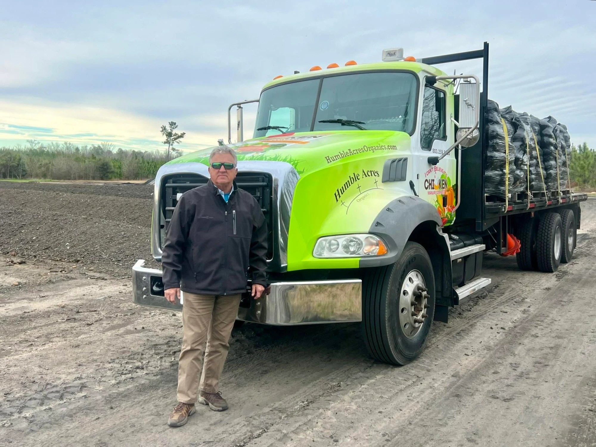 Tim McCormick standing in front of the Humble Acres delivery truck, loaded with bagged compost, on the yard at Blackville